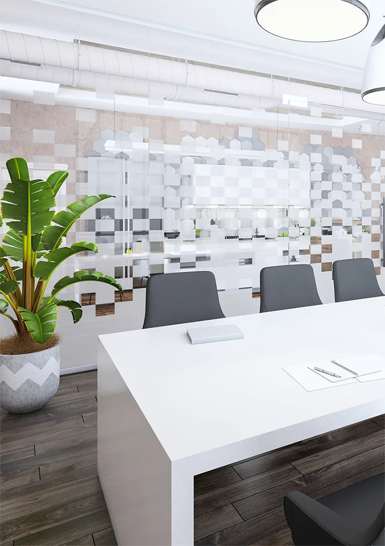 An empty conference room with white tables, gray chairs, house plant and a glass wall covered with decorative window film.