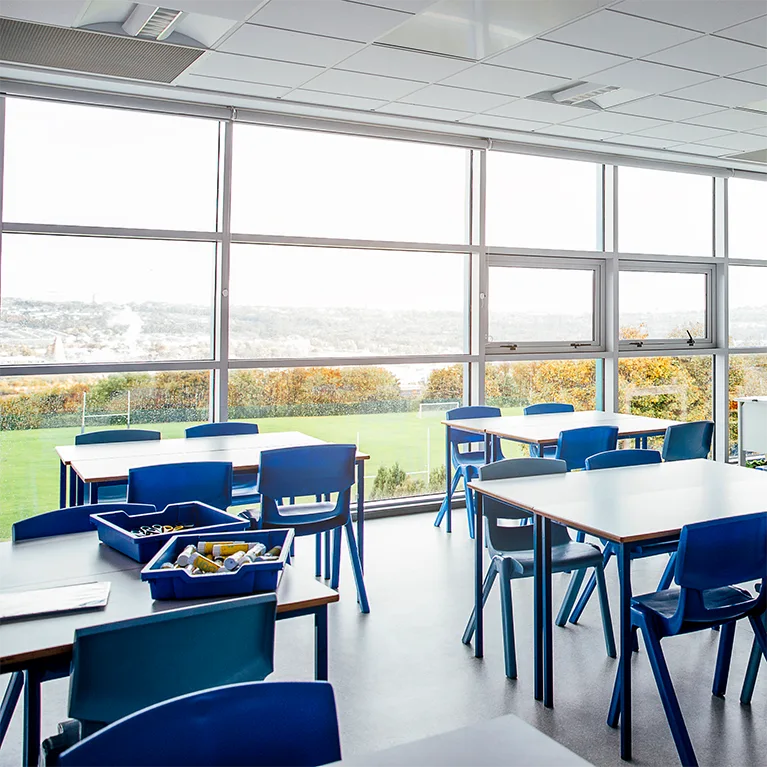 Large bay windows, which can be protected with 3M window film, cast light into a school classroom.