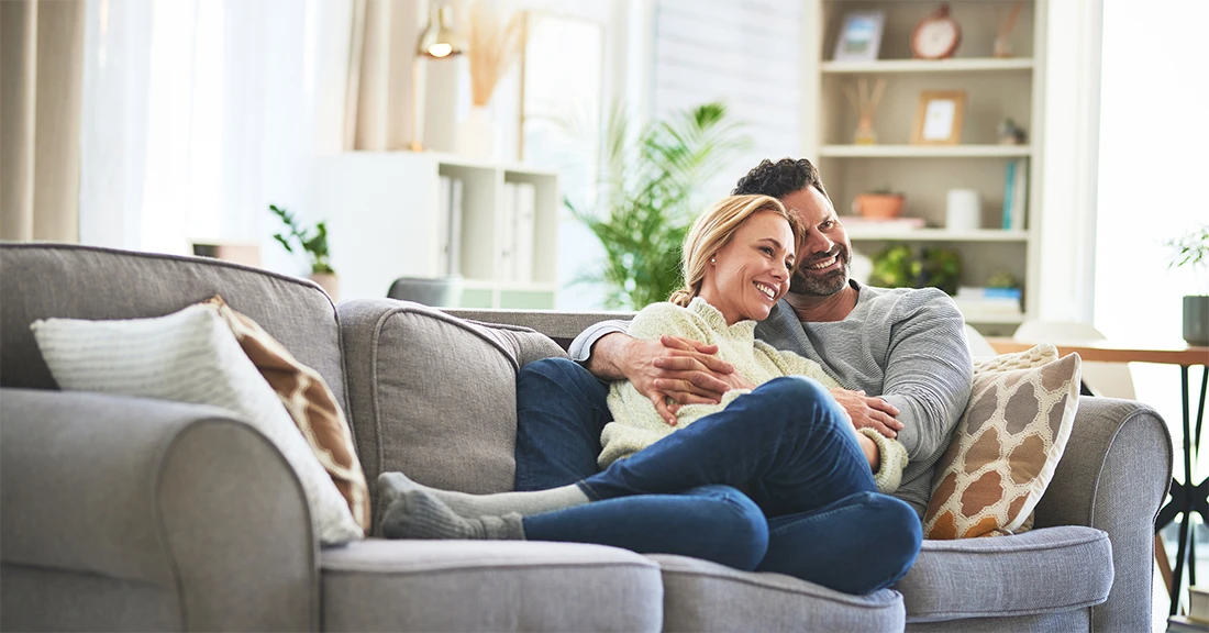 A couple relax on their couch in their home with home window tint in what could be The Villages, Florida