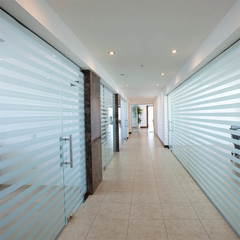 Glass divider walls down a hallway are covered with a decorative striped window film, like 3M Fasara Glass Finishes.