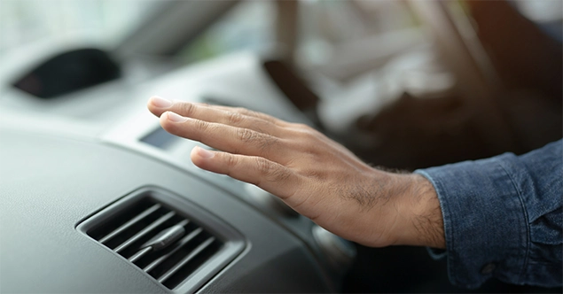 Hand reaches over automotive air conditioning event to cool off.