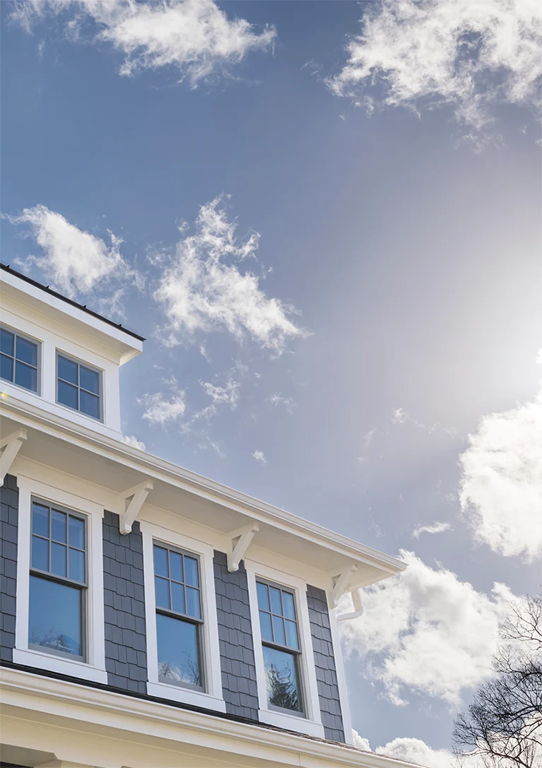 Sunshine is streaming on windows of a two-story home to illustrate how residential window tinting can tamper the harmful effects of the sun.